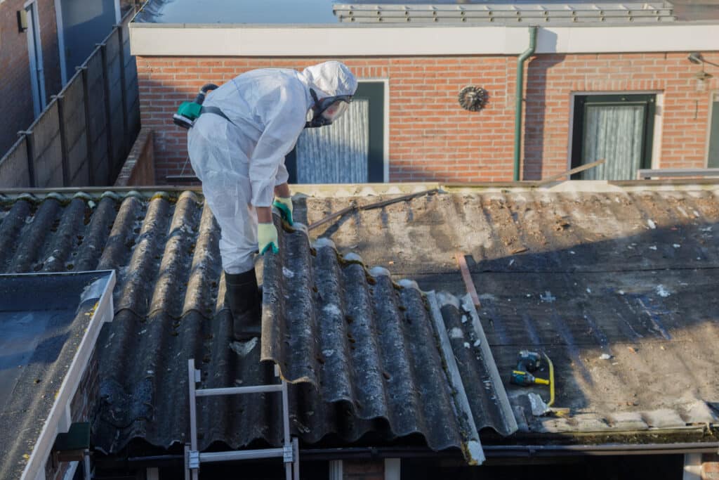 Professional asbestos removal. Men in protective suits are removing asbestos cement corrugated roofing. Avoid Asbestos